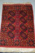 Small Afghan rug with a repeating gol design on red ground, 71cms x 54cms